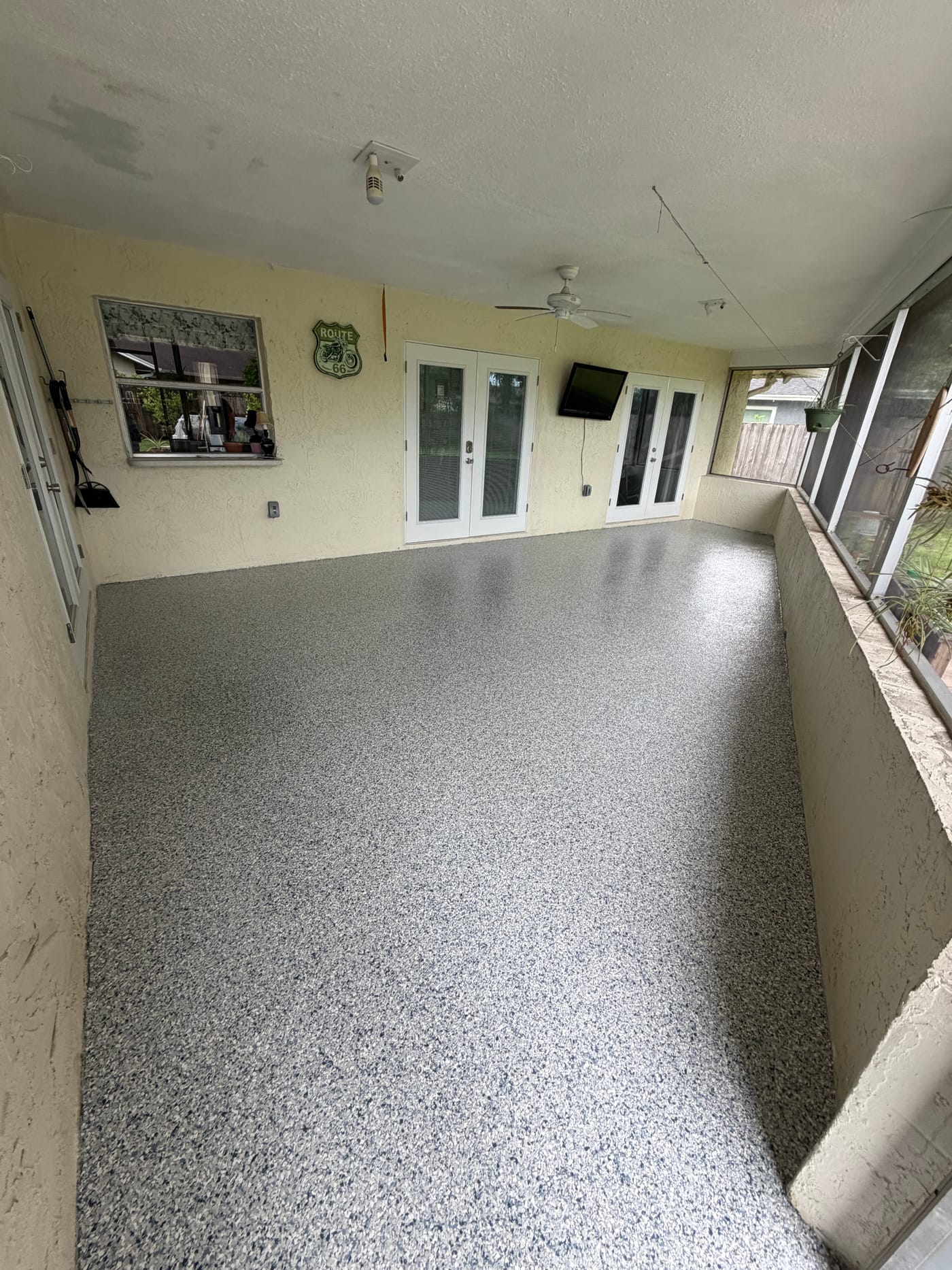 Screened patio floor after a light gray decorative flake coating installation.