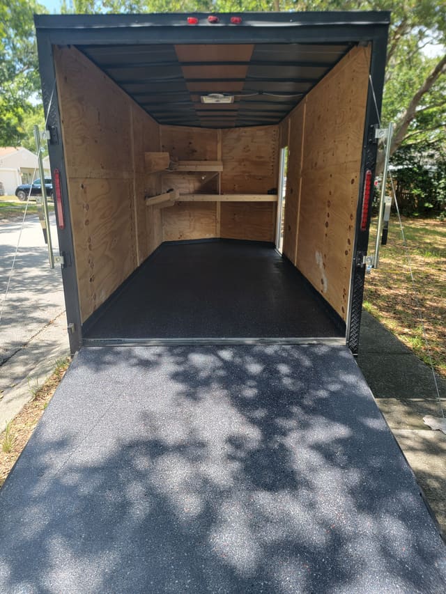 Utility trailer floor finished with a durable dark protective coating.