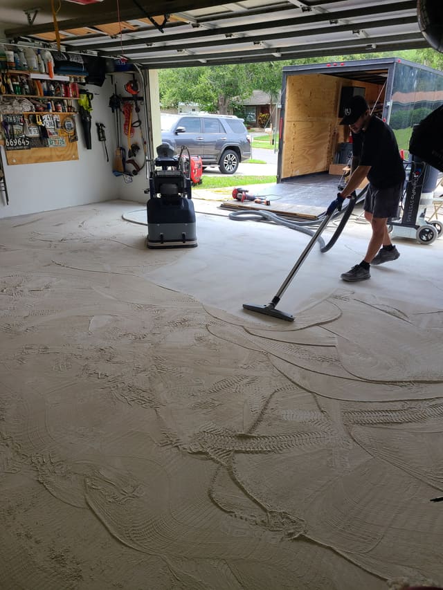 Garage concrete floor being diamond-ground and vacuumed before a coating installation.