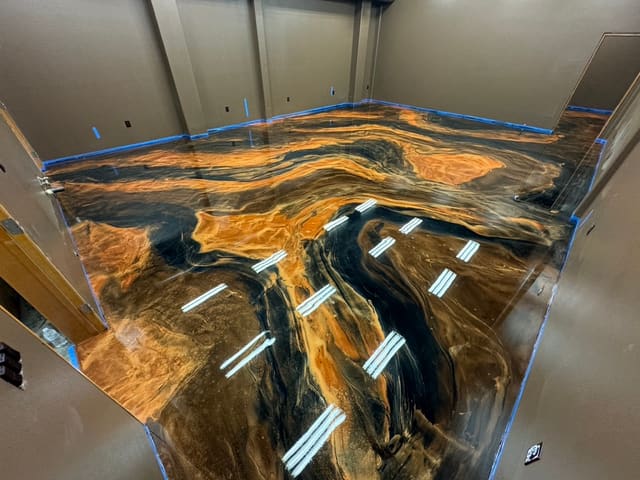 Custom metallic epoxy floor with black, gold, and blue movement.