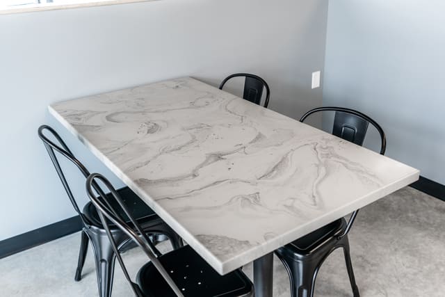 Dining table surface coated with a light marble-look epoxy finish.