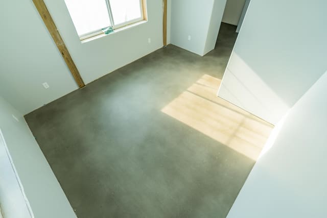 Interior concrete floor with a smooth gray coating in a bright room.