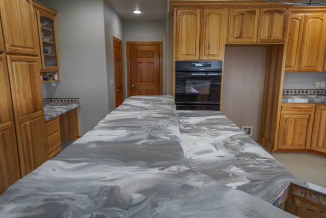 Kitchen countertop with a gray and white marble-look epoxy finish.