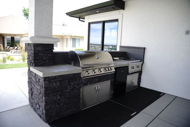 Outdoor kitchen countertop with a dark coating around a built-in grill.