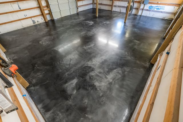 Glossy dark indoor epoxy floor coating inside a workshop.